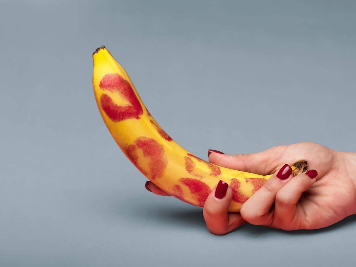 A hand holding a banana with red lipstick marks. Explore natural ways to manage erectile dysfunction for Filipino men at andyou.ph.