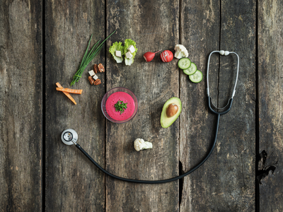 Healthy food and stethoscope forming a heart shape on rustic wooden table, symbolizing nutrition and heart health connection