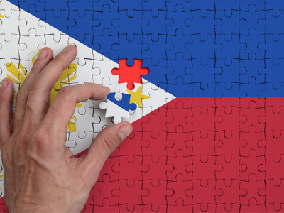A hand placing the final puzzle piece into a jigsaw puzzle depicting the flag of the Philippines, symbolizing the search for where to buy Wegovy in the country.