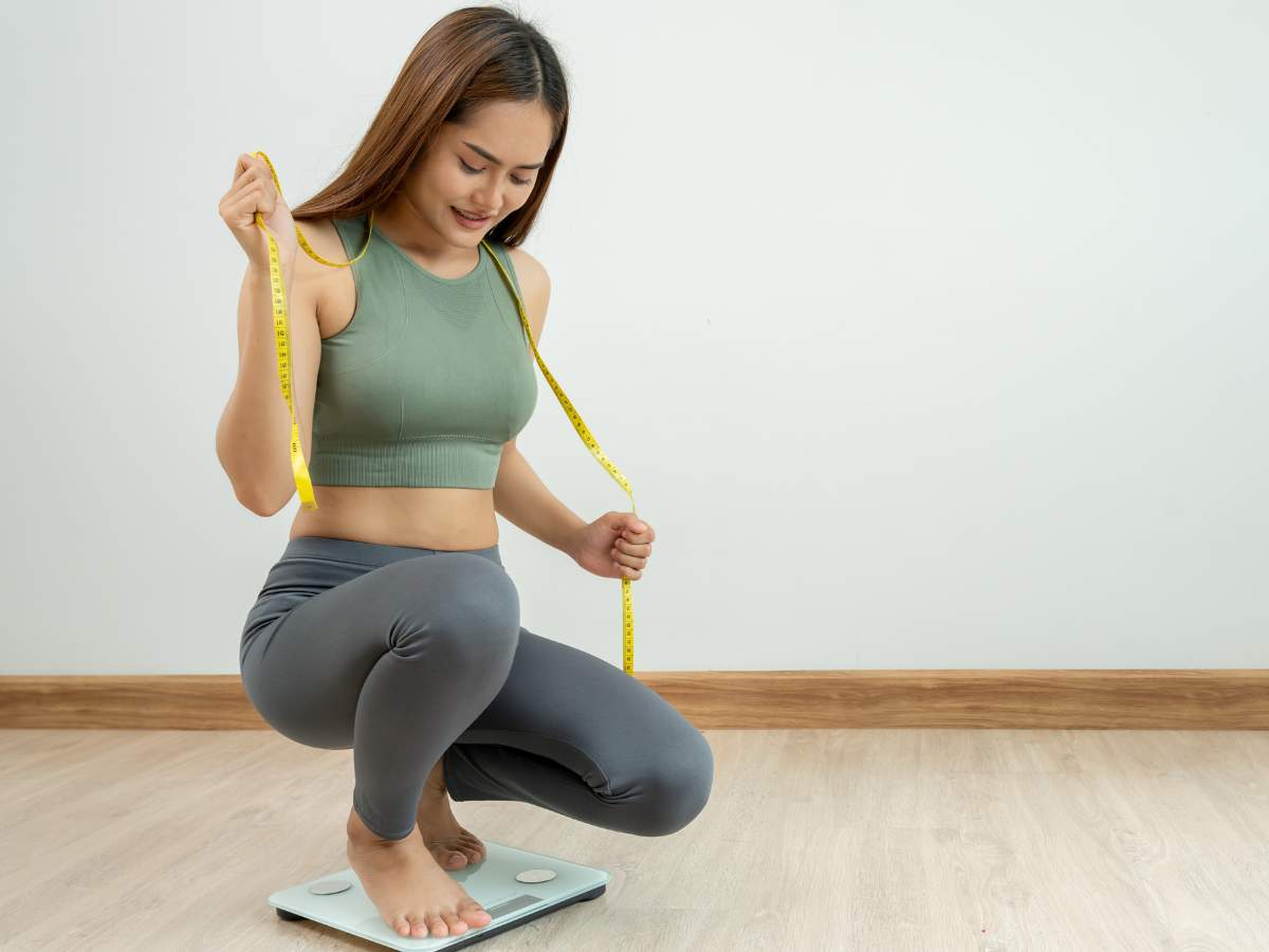 Filipina woman tracking weight loss progress with a scale and measuring tape. Discover sustainable weight loss tips tailored for Filipinos at andyou.ph.